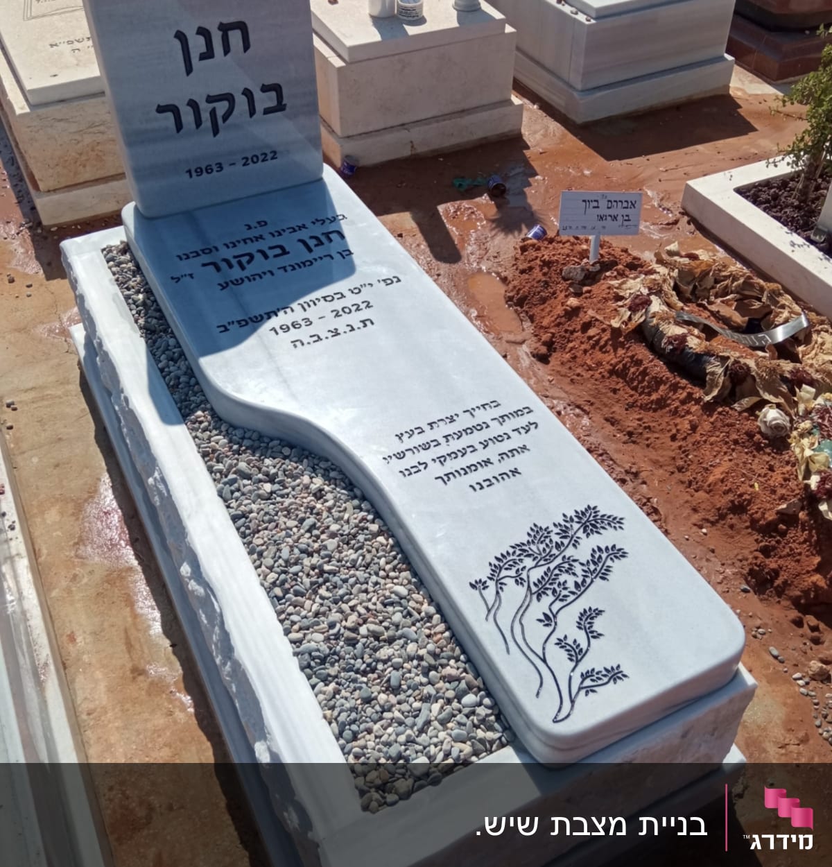 מצבה עם כיתוב בעברית ואבנים קטנות